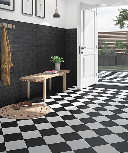 Modern interior with black and white checkered floor, wooden bench, and open door leading to garden.