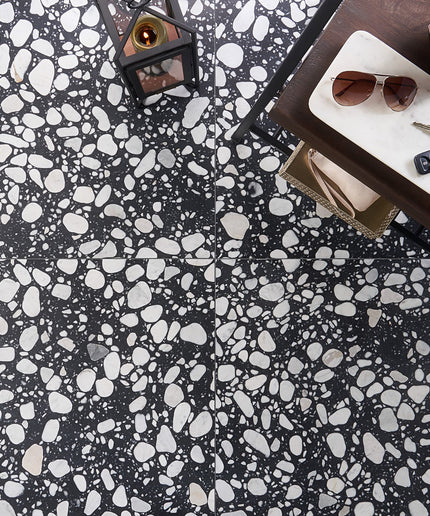 Black and white terrazzo patterned floor with a table and items on it.