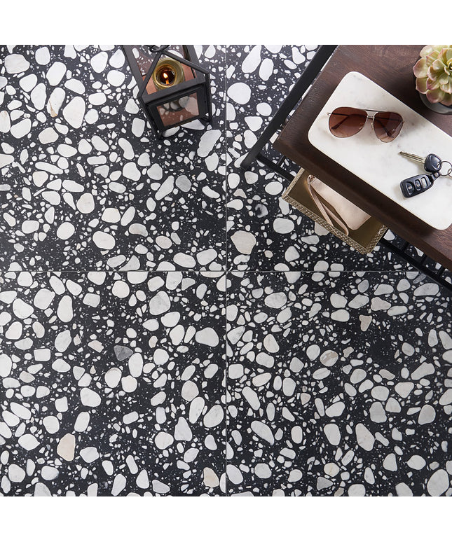 Black and white terrazzo patterned floor with a table and items on it.
