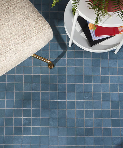 Blue tiled floor with a chair and small table in the corner