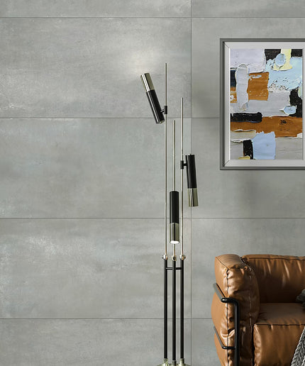 Modern floor lamp with abstract art on a gray wall above a brown sofa.