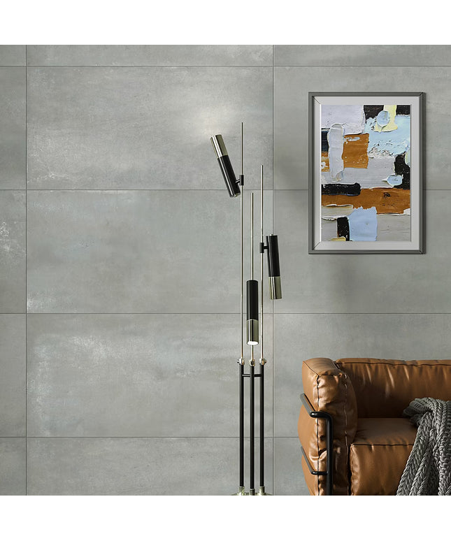 Modern floor lamp with abstract art on a gray wall above a brown sofa.