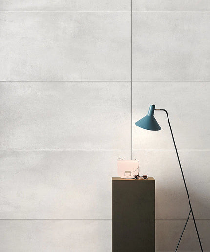 Modern interior design with a blue lamp and pink bag on a wooden stand against a gray tiled wall.