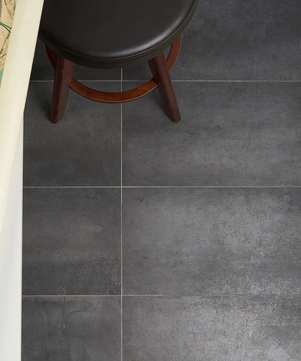 Dark gray tiles on a floor with a wooden stool and rolled-up map.