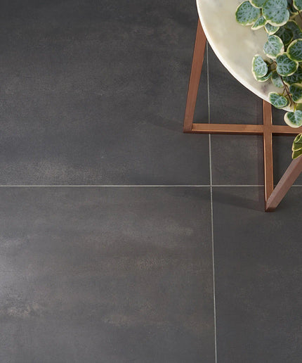 Dark gray tiles with a decorative plant and stand in the corner
