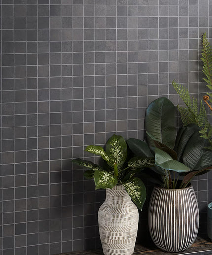 Three potted plants in front of a gray tiled wall