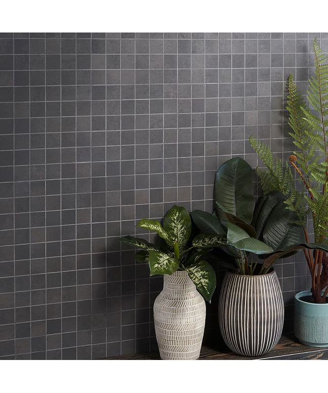 Three potted plants in front of a gray tiled wall
