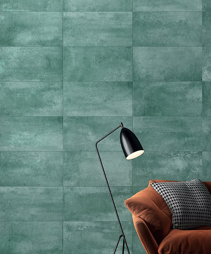 Green tiled wall with a brown sofa and black lamp