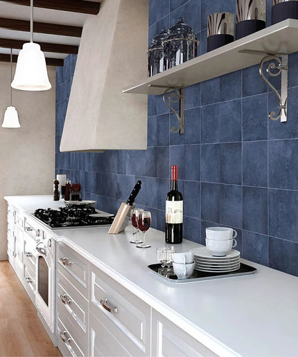 Modern kitchen with blue tiled wall, white countertops, and wine glasses.