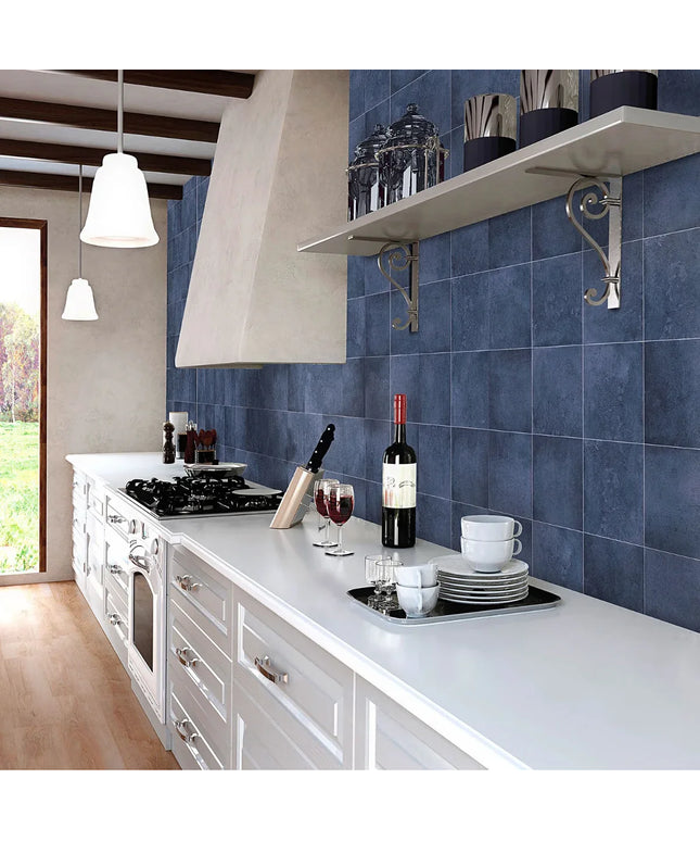 Modern kitchen with blue tiled wall, white countertops, and wine glasses.