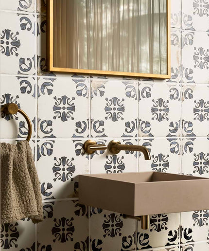 Patterned blue and white ceramic wall tiles in a modern bathroom with brass fixtures