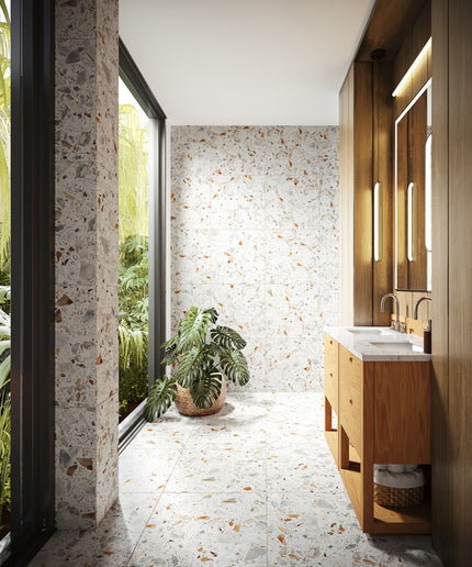 Modern bathroom with wooden vanity, mirror, and plants near a window with a view of greenery.