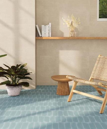 Modern interior with a wicker chair, potted plants, and a small table on a blue tiled floor.
