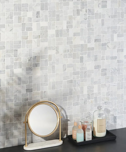 Carrara antique natural stone wall tiles with cosmetics, mirror, and tray on black counter
