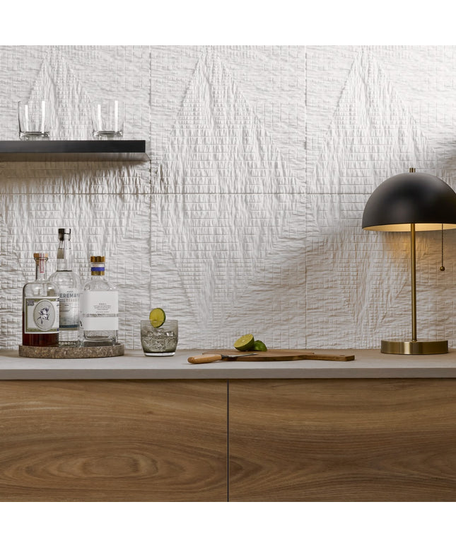 Modern kitchen counter with bottles, glasses, and a cutting board against a textured wall.