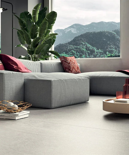 Modern living room with a gray sectional sofa, red cushions, and a view of mountains.