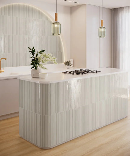 Modern kitchen with glossy vertical striped wall tiles, white island, and pendant lighting