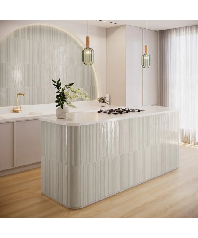 Modern kitchen with glossy vertical striped wall tiles, white island, and pendant lighting