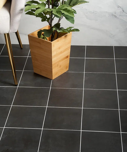 Black tiled floor with a wooden planter and plant against a marble wall.