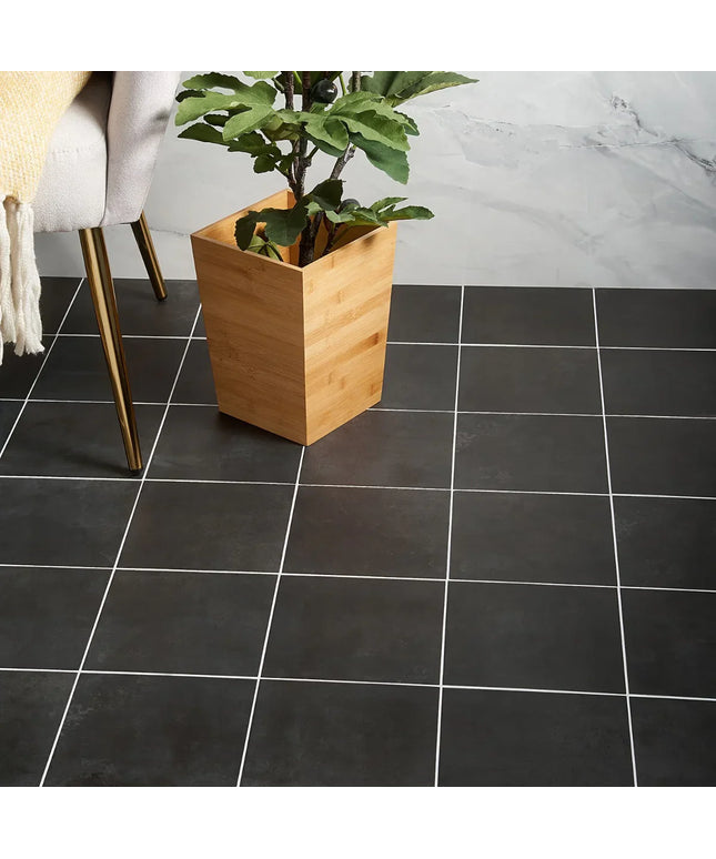 Black tiled floor with a wooden planter and plant against a marble wall.
