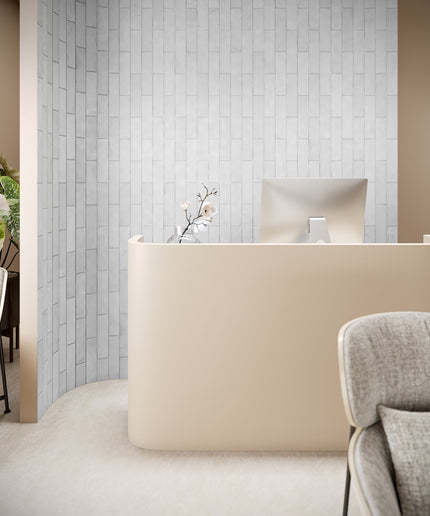 Modern office reception area with a beige desk and gray chairs.