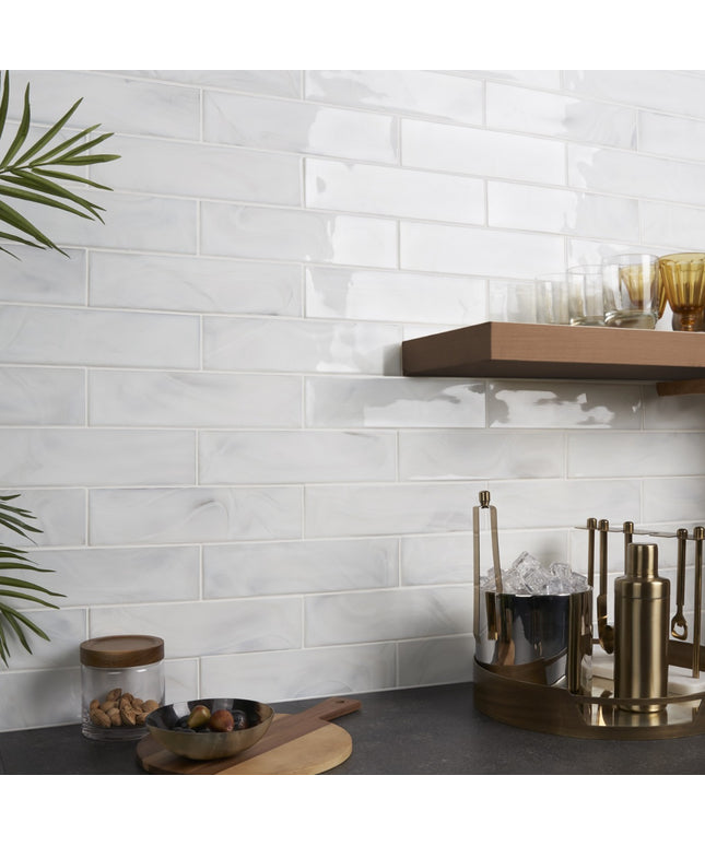 Kitchen counter with white tiled wall, wooden shelf, and decorative items.