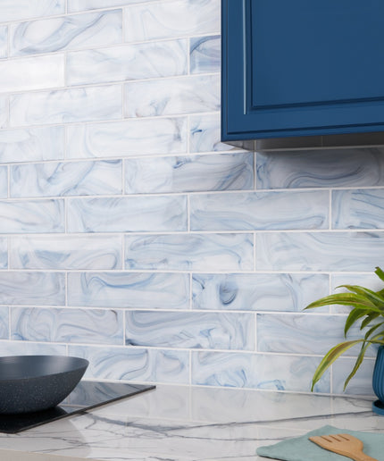 Kitchen with blue and white marbled tiles on the wall, a plant, and kitchen utensils.