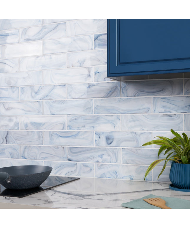 Kitchen with blue and white marbled tiles on the wall, a plant, and kitchen utensils.