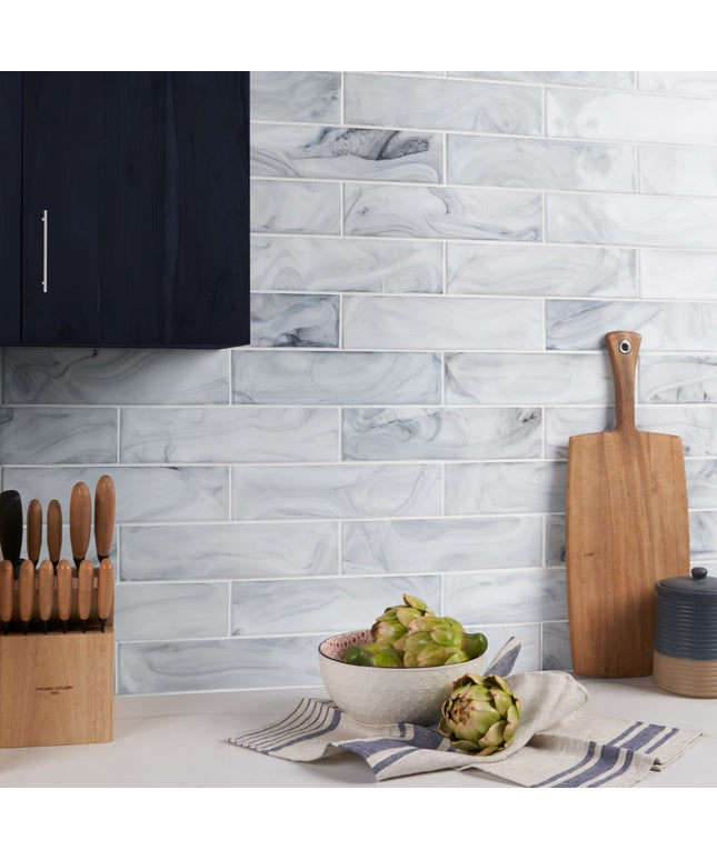 Kitchen scene with marble tile backsplash, cutting board, and fruit bowl.
