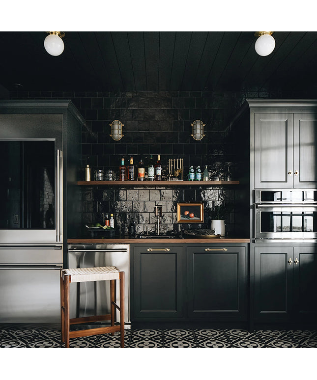 Modern kitchen with dark cabinets, black tiled walls, and stainless steel appliances.