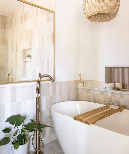 Modern bathroom with a freestanding bathtub, wooden tray, and decorative elements.