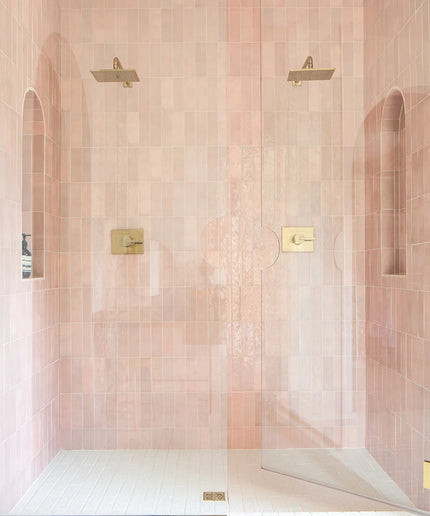 Shower enclosure with pink tiles and gold fixtures