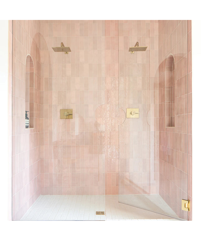 Shower enclosure with pink tiles and gold fixtures
