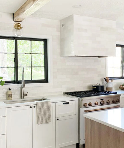 Modern kitchen with white cabinets, stainless steel appliances, and a window above the sink.