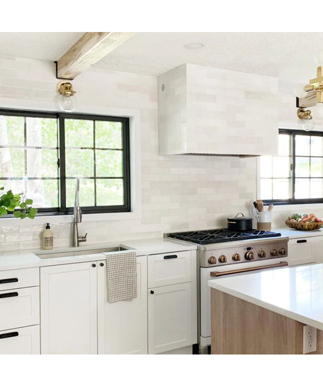 Modern kitchen with white cabinets, stainless steel appliances, and a window above the sink.