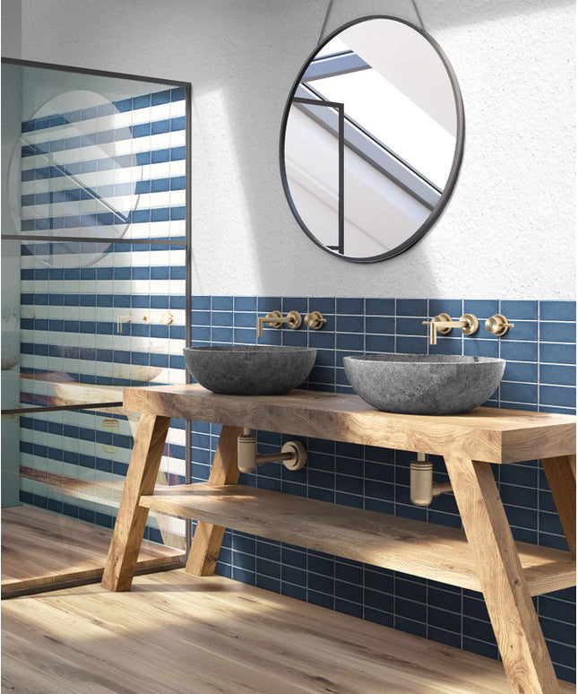 Modern bathroom with blue rectangular wall tiles, vessel sinks, wood vanity, and round mirror