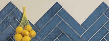 Bag of lemons and a banana on a blue tiled floor herringbone design