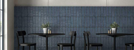 Modern interior with black tables and chairs against a blue tiled wall.