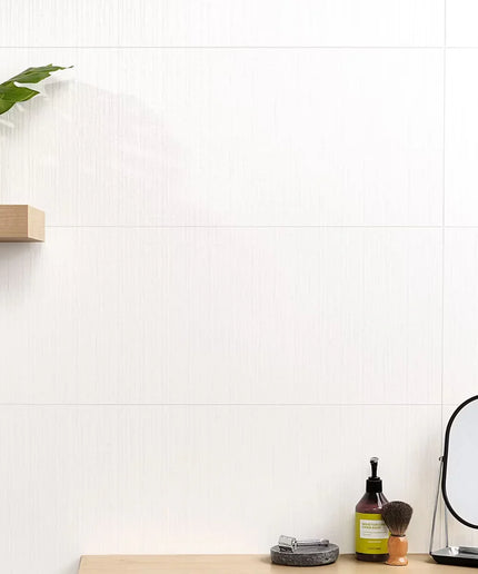 Small vanity setup with mirror, bottle, and plant on a white tiled wall background