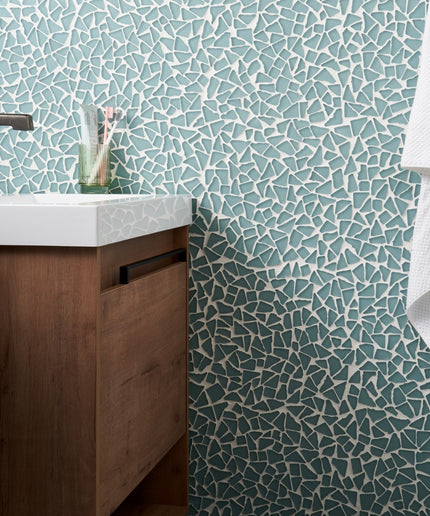 Bathroom with mosaic tile wall, wooden vanity, and white towel.