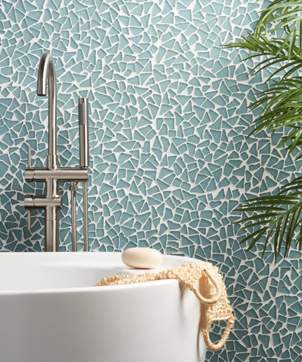 Bathroom setting with mosaic tile wall, white bathtub, and plant