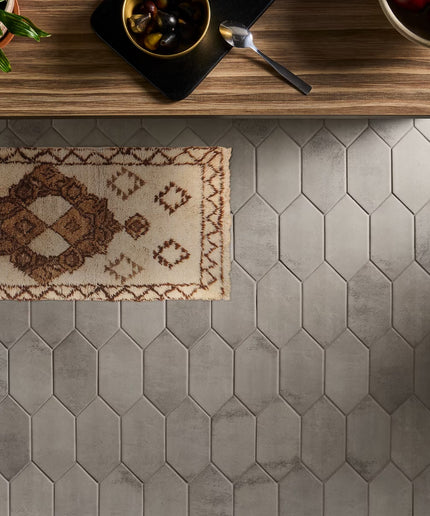 Hexagonal tile floor with a small rug on a wooden surface