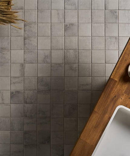 Gray tiled wall with a wooden shelf and white sink