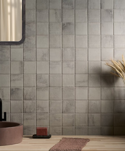 Bathroom with gray tiled walls, a sink, and a plant.