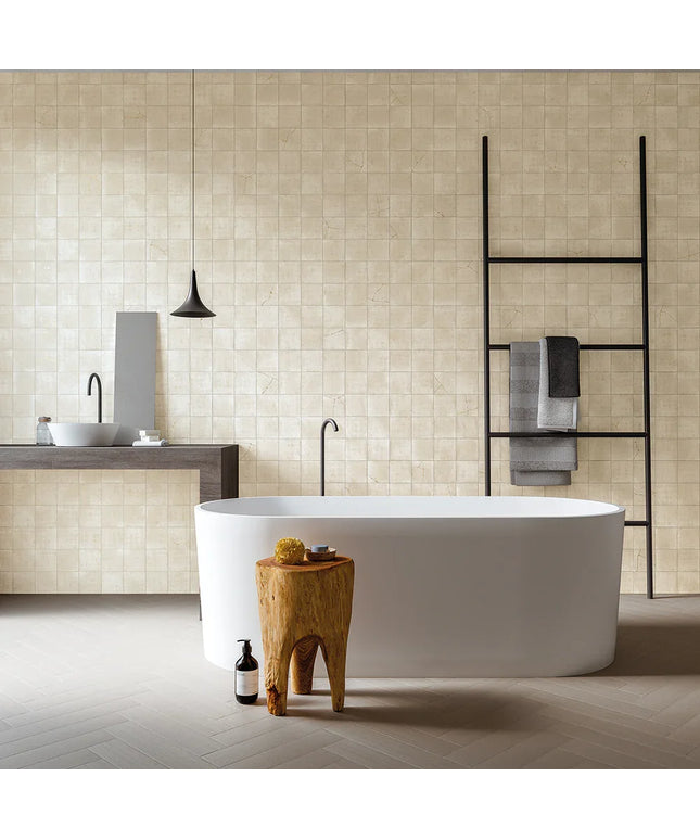 Modern bathroom with a freestanding bathtub, wooden stool, and tiled walls.
