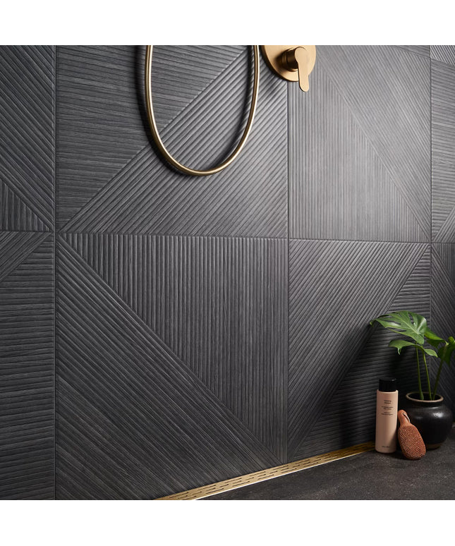Gray textured tiles with a gold shower head and accessories on a bathroom wall.