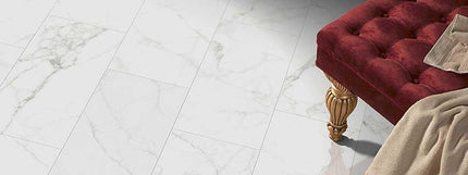 Marble floor with a red cushioned ottoman and beige rug.
