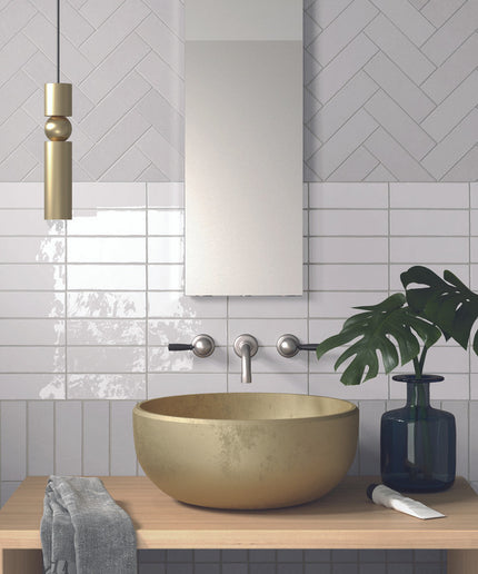 Modern bathroom vanity with beige vessel sink, glossy white wall tiles, and herringbone backsplash.