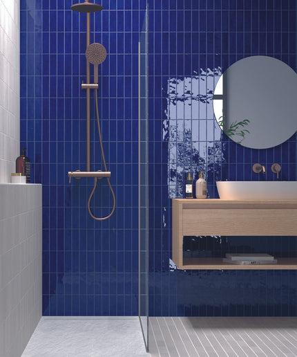 Modern bathroom with glossy blue vertical tiles, wood vanity, and rainfall shower