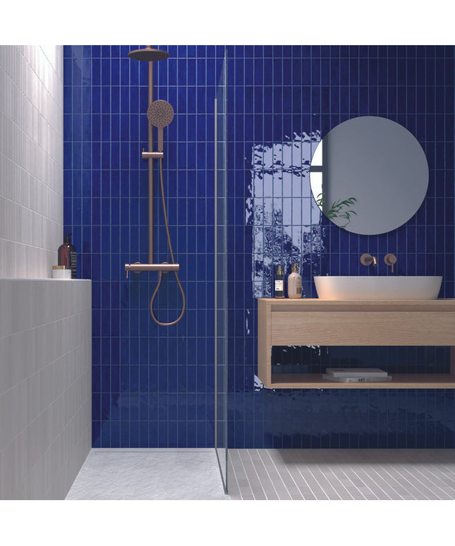 Modern bathroom with glossy blue vertical tiles, wood vanity, and rainfall shower